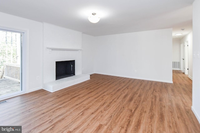 unfurnished living room featuring a brick fireplace and light hardwood / wood-style flooring