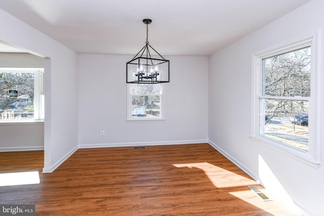 unfurnished dining area with dark wood-type flooring and a notable chandelier