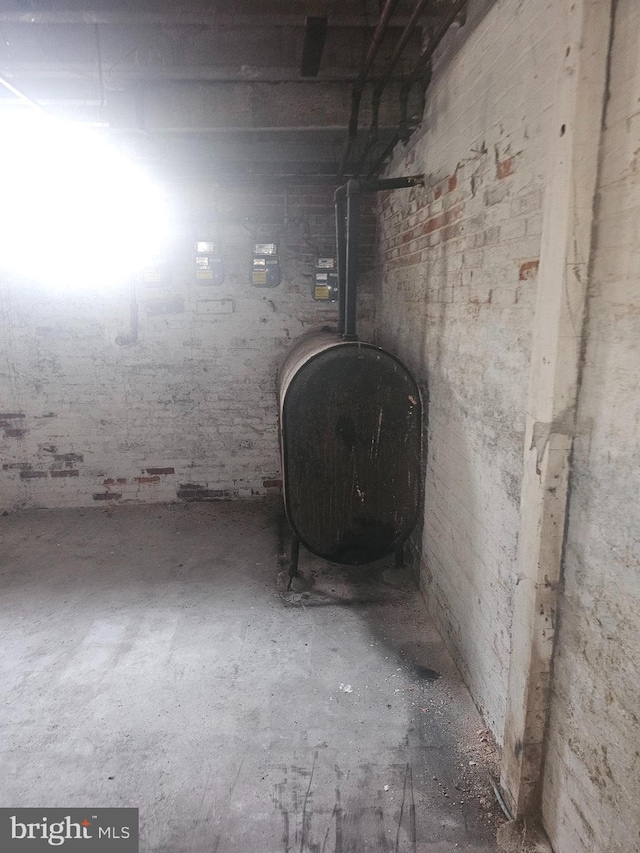 unfinished basement featuring a wood stove and heating fuel