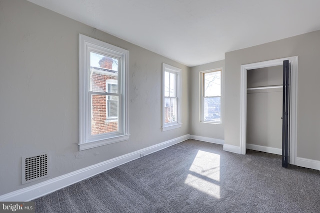 unfurnished bedroom with dark colored carpet and a closet