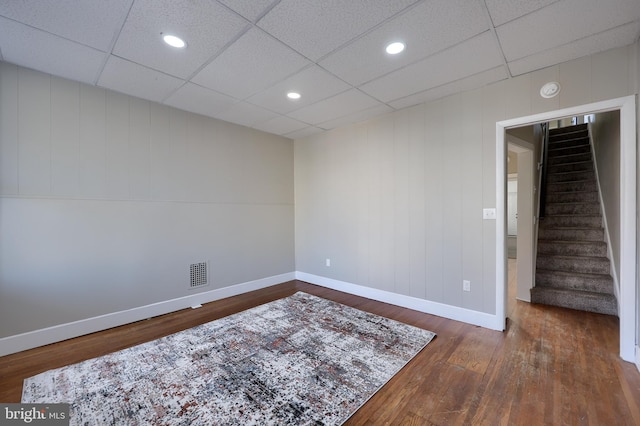 unfurnished room featuring dark wood-type flooring and a drop ceiling