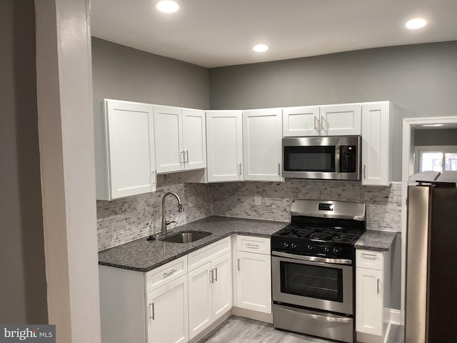 kitchen with tasteful backsplash, stainless steel appliances, sink, and white cabinets