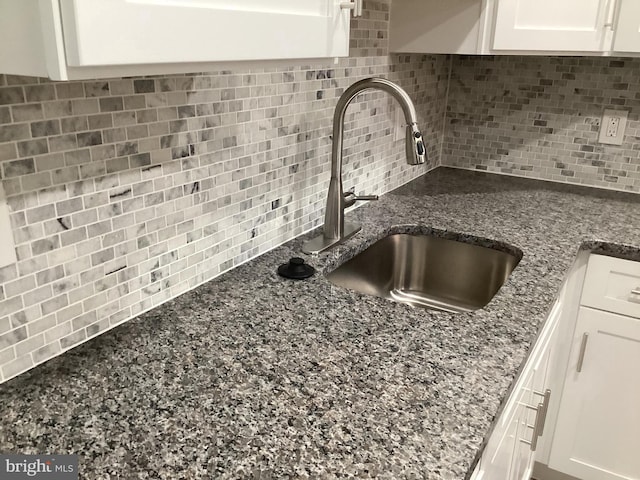 details with white cabinetry, sink, backsplash, and dark stone counters