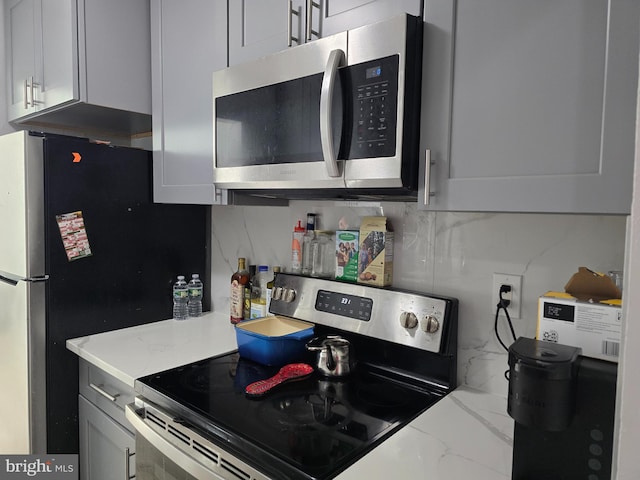 kitchen featuring light stone countertops, marble finish floor, tasteful backsplash, and stainless steel appliances