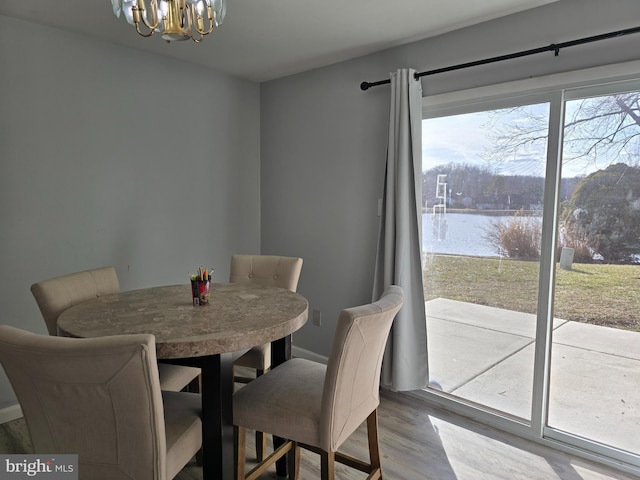 dining room featuring wood finished floors, a water view, and an inviting chandelier