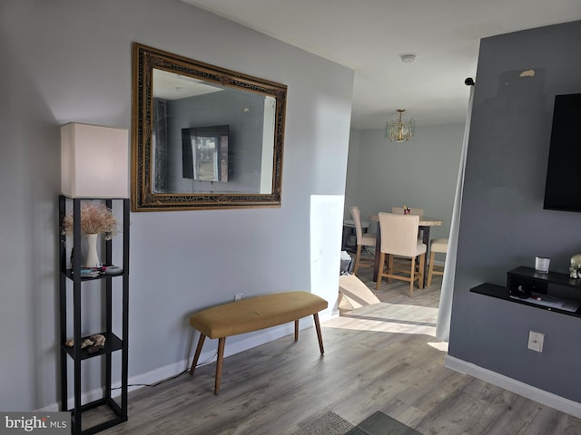 corridor featuring a notable chandelier, wood finished floors, and baseboards