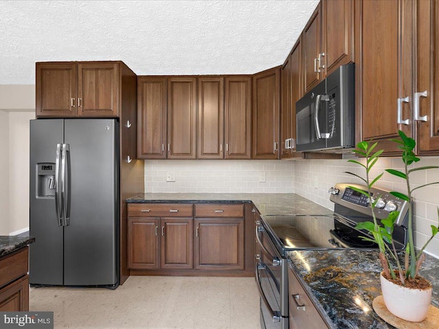 kitchen with light floors, dark stone counters, appliances with stainless steel finishes, a textured ceiling, and tasteful backsplash