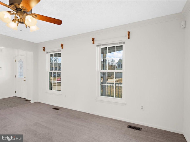 carpeted spare room with visible vents, a healthy amount of sunlight, a textured ceiling, and baseboards