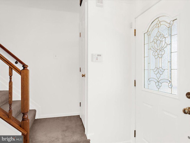 carpeted entryway featuring stairs and baseboards