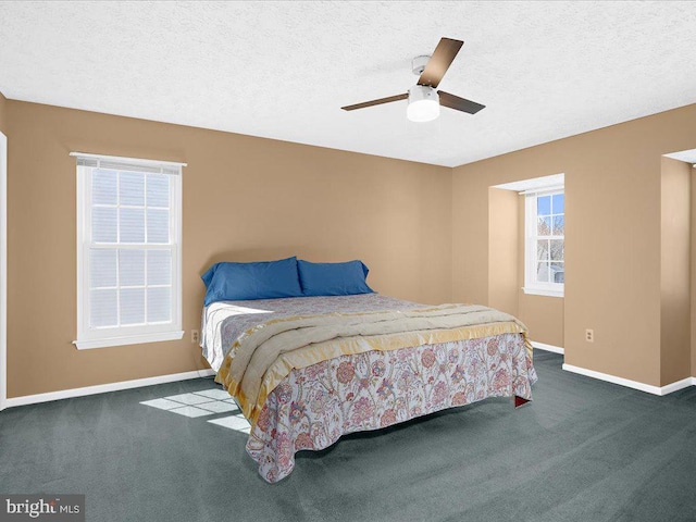 carpeted bedroom with ceiling fan, baseboards, and a textured ceiling