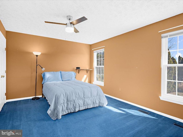 carpeted bedroom with visible vents, multiple windows, and baseboards