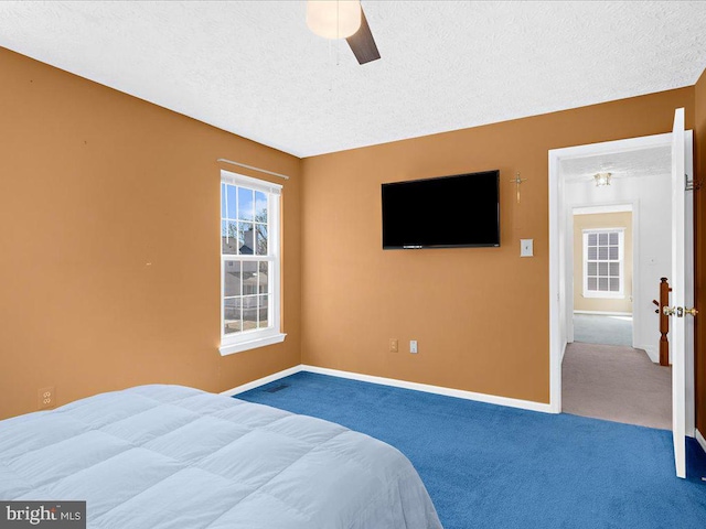 bedroom featuring ceiling fan, a textured ceiling, baseboards, and carpet floors