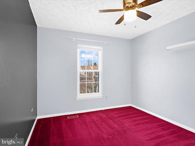 carpeted spare room featuring visible vents, baseboards, a textured ceiling, and a ceiling fan