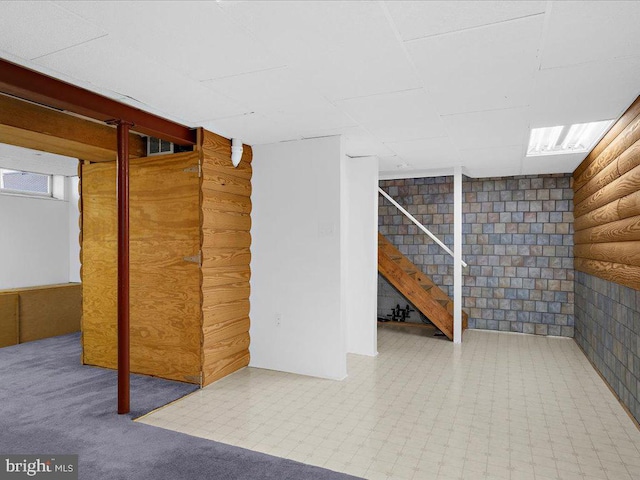 finished basement featuring stairs and tile patterned floors