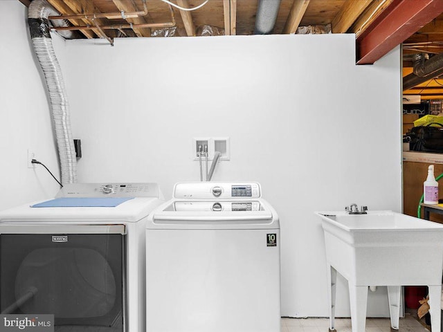 washroom with laundry area, washing machine and dryer, and a sink