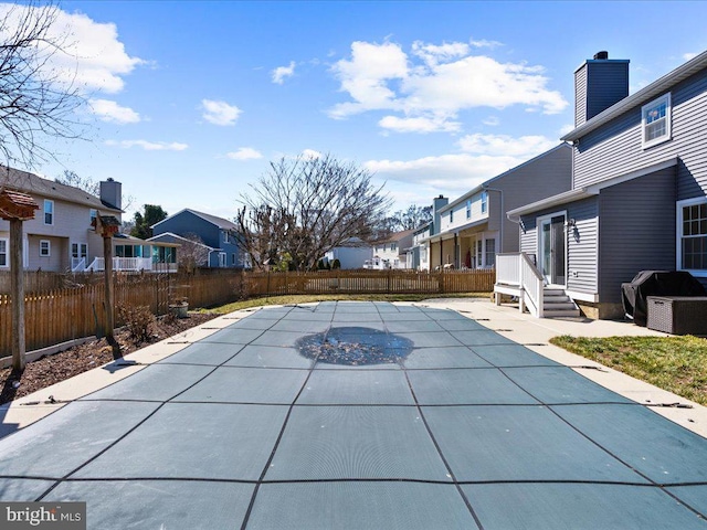 view of swimming pool with a patio, a fenced backyard, a residential view, and grilling area