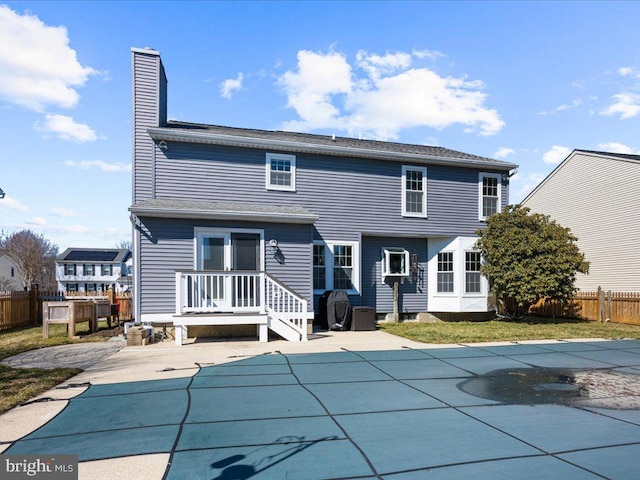 back of house featuring a patio, fence, a fenced in pool, and a chimney