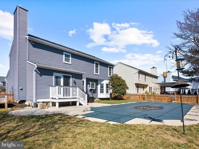 rear view of house featuring a patio area, a yard, fence, and a chimney