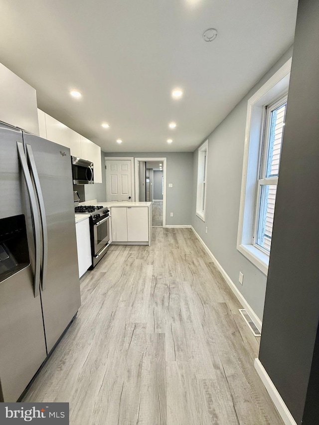 kitchen featuring white cabinetry, stainless steel appliances, and light hardwood / wood-style flooring