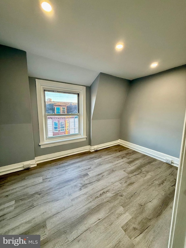 bonus room with hardwood / wood-style flooring and vaulted ceiling