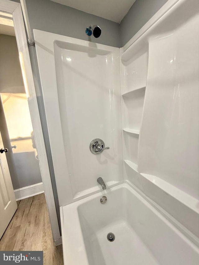 bathroom featuring wood-type flooring and bathtub / shower combination