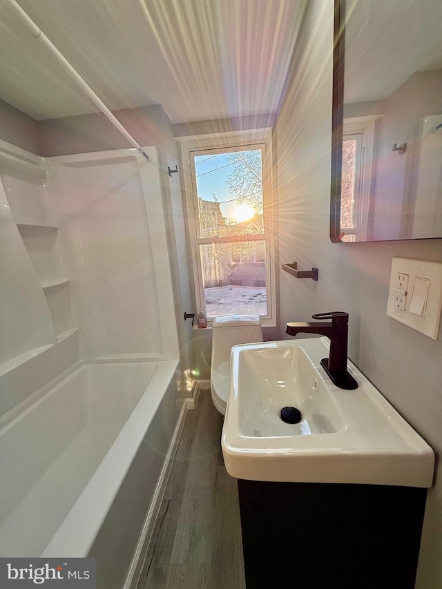 full bathroom featuring wood-type flooring, sink, tub / shower combination, and toilet