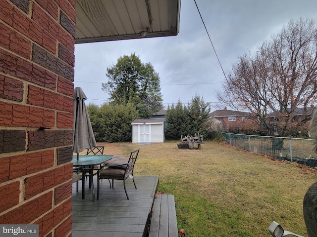 view of yard with a storage shed, fence, a deck, outdoor dining area, and an outdoor structure