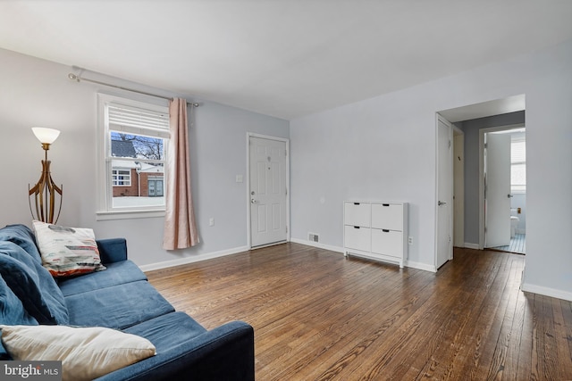 living room with plenty of natural light and dark hardwood / wood-style flooring