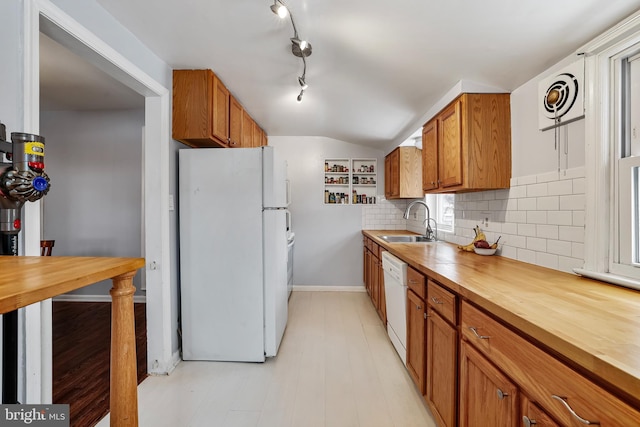 kitchen with lofted ceiling, sink, white appliances, butcher block counters, and decorative backsplash