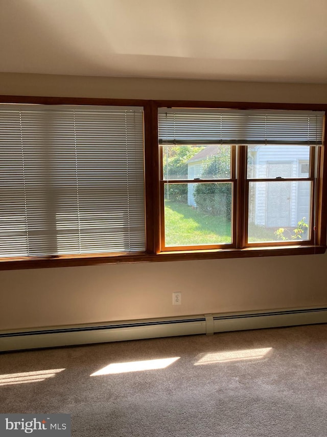 carpeted empty room featuring baseboard heating