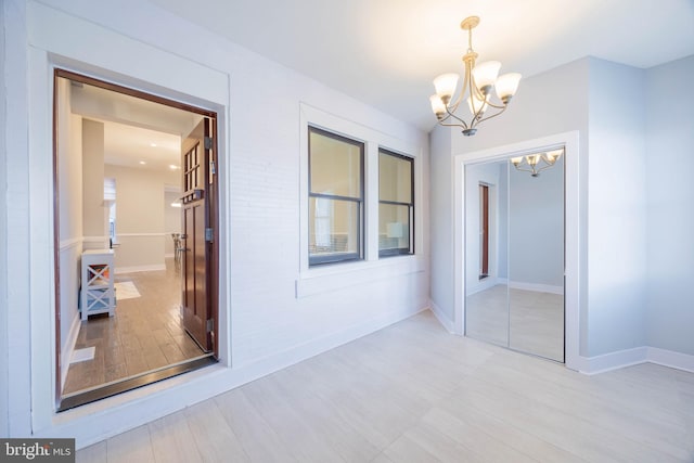 interior space featuring an inviting chandelier, baseboards, and light wood finished floors