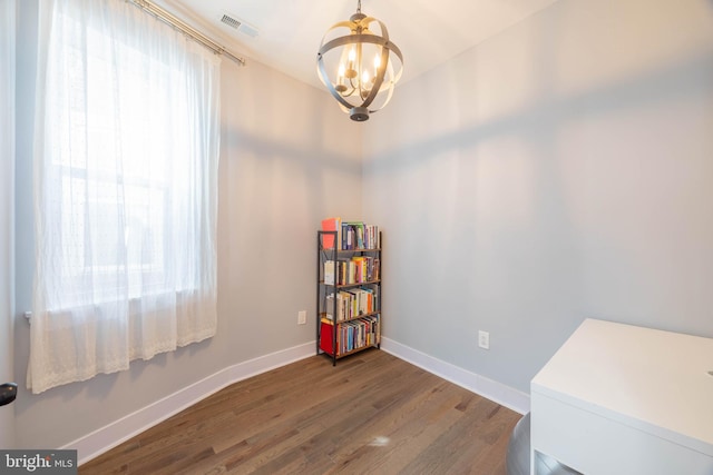 interior space with baseboards, visible vents, a chandelier, and wood finished floors