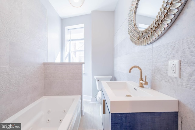 bathroom with a whirlpool tub, toilet, tile walls, and vanity