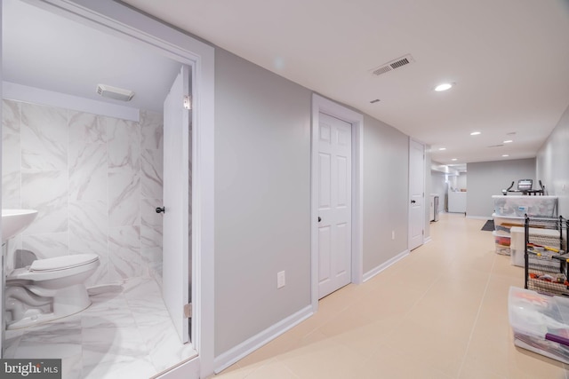 corridor featuring baseboards, visible vents, tile walls, and recessed lighting