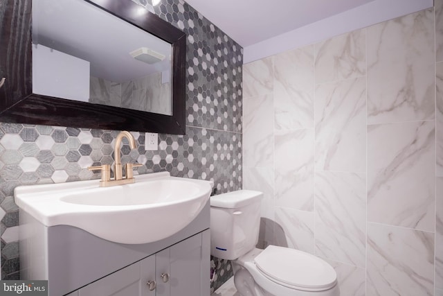 bathroom featuring tasteful backsplash, tile walls, vanity, and toilet