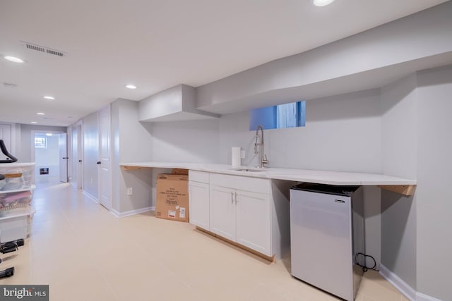 bar featuring baseboards, visible vents, freestanding refrigerator, a sink, and recessed lighting