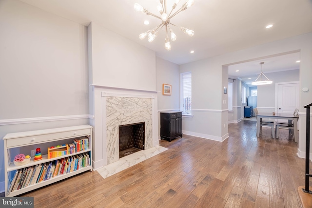 living room with recessed lighting, a high end fireplace, baseboards, hardwood / wood-style floors, and an inviting chandelier