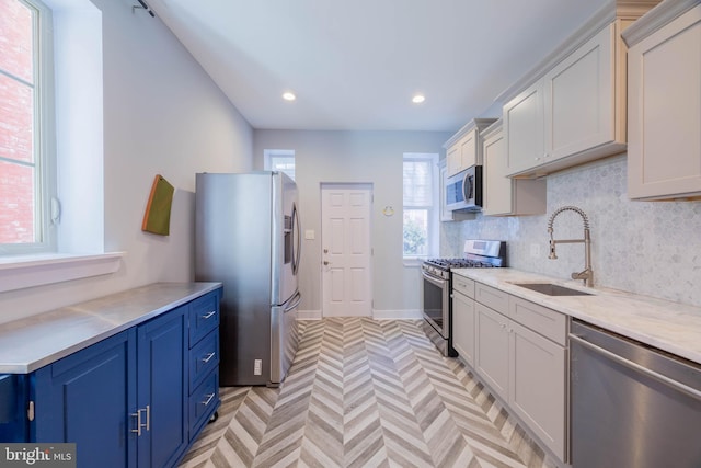 kitchen featuring blue cabinets, a sink, light countertops, appliances with stainless steel finishes, and decorative backsplash