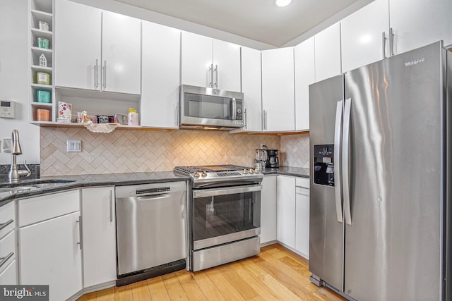 kitchen featuring light wood-style flooring, stainless steel appliances, white cabinetry, open shelves, and a sink