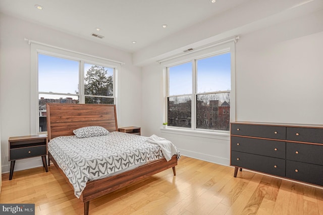 bedroom featuring visible vents, light wood finished floors, and multiple windows