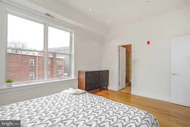 bedroom with visible vents, baseboards, and wood finished floors