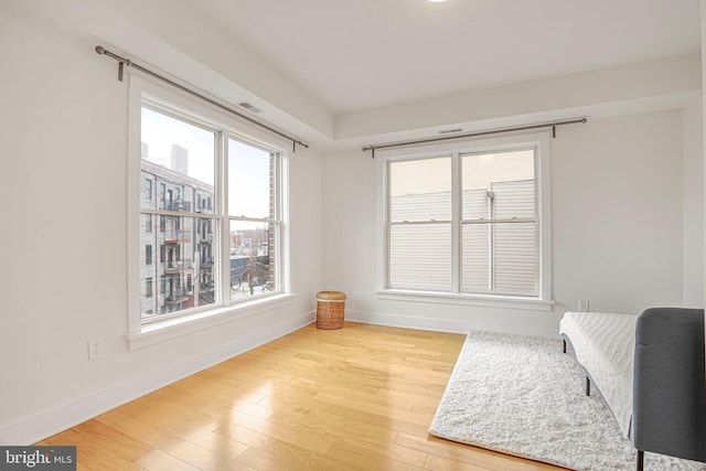 living area with wood finished floors, visible vents, and baseboards