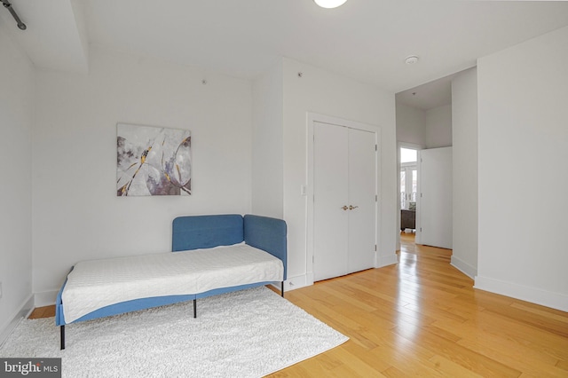 bedroom featuring light wood finished floors, baseboards, and a closet