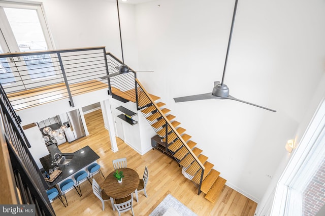 stairs with plenty of natural light, wood finished floors, a ceiling fan, and baseboards