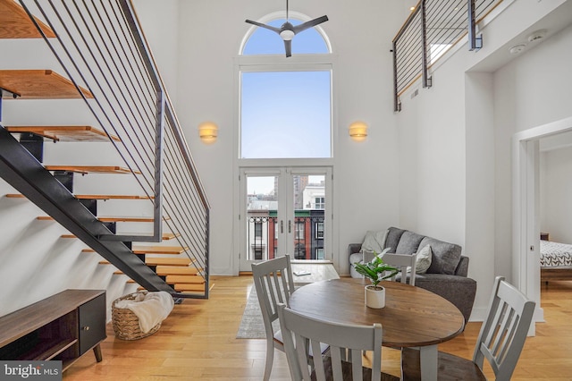 dining space featuring light wood-style floors, stairs, a high ceiling, and french doors