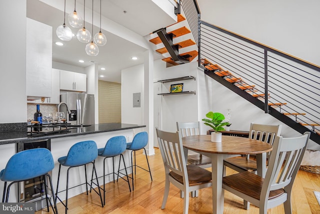 dining area featuring electric panel, light wood-style floors, stairs, and recessed lighting