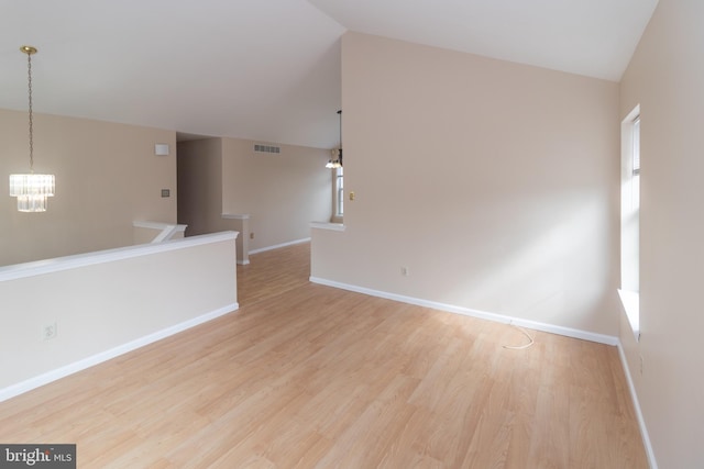 unfurnished room featuring vaulted ceiling, wood finished floors, and a notable chandelier