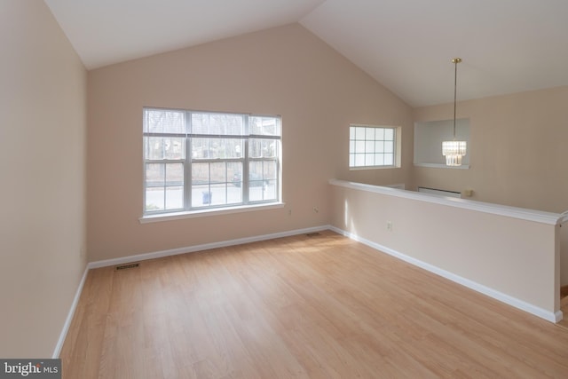 spare room featuring a notable chandelier, visible vents, baseboards, vaulted ceiling, and light wood-type flooring