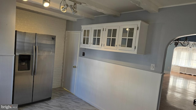 kitchen featuring beamed ceiling, stainless steel refrigerator with ice dispenser, glass insert cabinets, and white cabinets