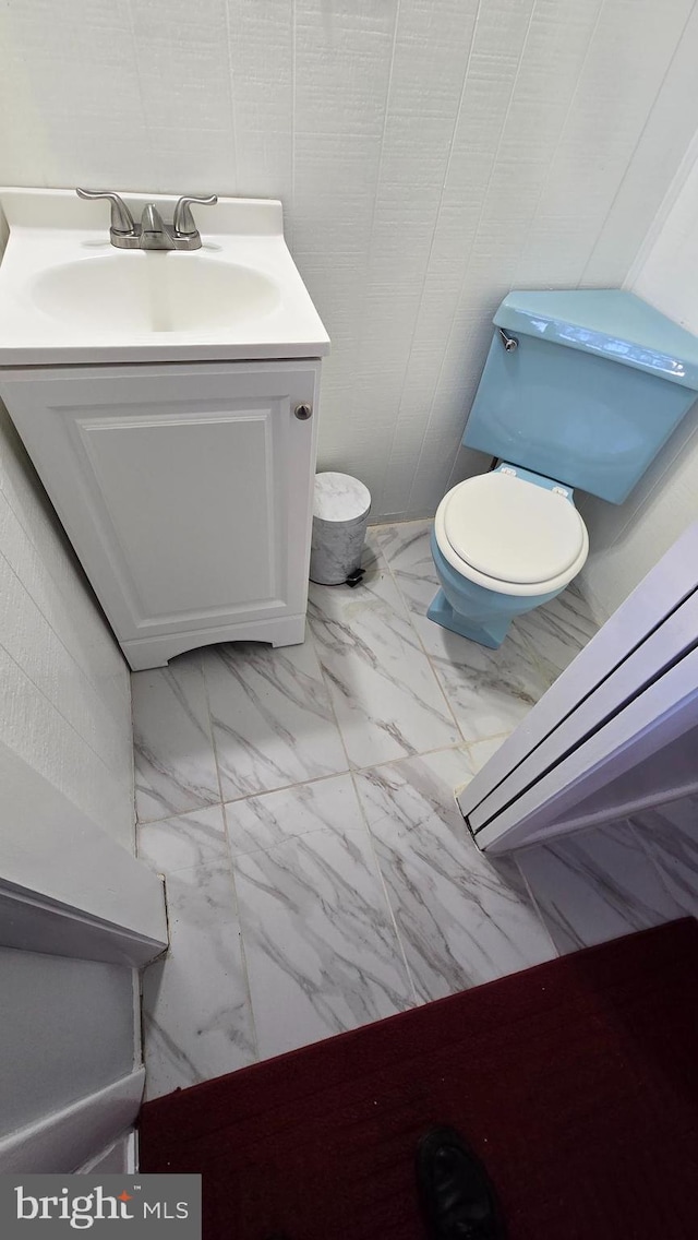 bathroom with toilet, marble finish floor, and vanity